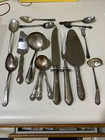 Overview of all 16 sterling silver pieces including spoons and serving utensils.