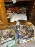 Plastic bags containing floral paper napkins and fabric linens stacked inside a wooden cabinet