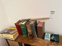 Side view of the collection showing variety of book sizes and colors including a large green dictionary and cookbooks scattered around