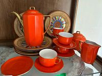 Full set arranged showing coffee pot, cups, saucers, creamer, sugar bowl, and Asian style plates in background.