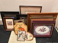 Seven vintage framed prints and plaques arranged against a wall showing various frame styles and sizes