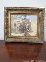 Framed painting showing man and donkey in rural scene.