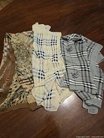 Three scarves laid on wooden surface showing patterns and colors