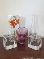 Photo showing two clear glass cubical candlesticks by Goran Warff, Dansk vase in box, purple-pink Bohemian vase, and tall clear Krosno vase