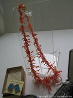 Full view of the coral branch necklace displayed on clear stand, showing coral pieces and clasp. Includes box with earrings.