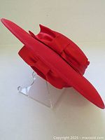 Side angle showing the wide brim and satin bow wrap on the red tilt hat.