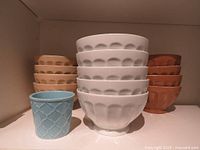Front view of all 13 items: stacked white bowls, beige bowls, brown bowls, and small blue cup in front.