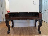 Front view of rosewood writing desk with flip-top open showing interior cubbyholes and carved legs