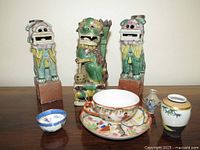 Three polychrome Foo Dog figures on wooden table