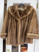 Front view of vintage tan mink fur jacket showing plush fur and classic cut with sleeves and collar visible.