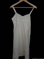 Full view of white vintage cotton sundress with eyelet embroidery, thin straps, and scalloped edges.