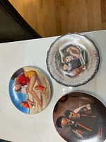 Top view of three collector plates showing their artwork and size, including the 'Always Sisters, Forever', Marilyn Monroe, and the accordion player plates.