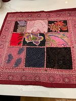 Close view of one pillow cover showing patchwork of embroidered and embellished floral designs with maroon border.