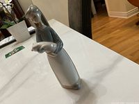 Side angle of the glossy porcelain figurine depicting a girl holding a pig, showing detailed view of the figure's colors and shape