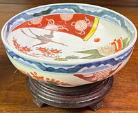 Angled side view of the bowl highlighting the painted crane, floral patterns and contrasting border designs on the rim.