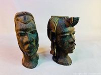 Pair of vintage African carved wooden busts, male and female, showing side-by-side with wood grain and carving detail visible.
