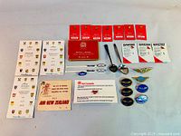 Wide view of the collection showing boxed Air Canada pins, Qantas pins, spoons, airline wings pins, Wardair branded stir sticks, and ephemera.