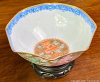 Full view of scalloped-rim bowl on wooden stand showing overall shape and decoration