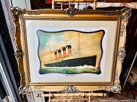 Framed print of Lusitania with ornate gold frame and some wear visible on frame corners.