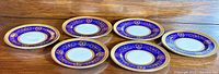 Six Coalport Lady Anne Cobalt Blue bread and butter plates arranged on a wooden surface.