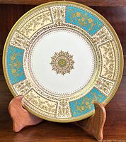 Full front view of the cabinet plate on wooden stand showing overall design and condition