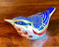 Side view of the Royal Crown Derby nuthatch bird paperweight showing detailed blue, gold, and red paintwork and small chip on beak tip visible.
