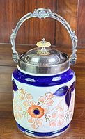 Front view of the Victorian Imari biscuit barrel showing the cobalt blue and orange floral design and EPNS lid with attached handle.