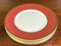 Stack of six dinner plates showing marone border with gold trim