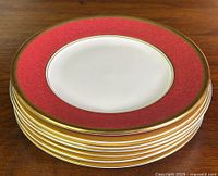 Stack of six maroon and gold accented Coalport salad/luncheon plates viewed from top showing the decorative rim