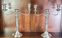 Pair of vintage EPNS three-arm silver candelabra shown front-facing on wooden background