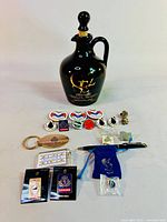 Full assortment of QE2 souvenirs including porcelain jug, pins, keychain, pen, and souvenir cards.