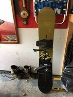 Full view of the Evolution snowboard with attachments and Limited boots on the floor beside it.