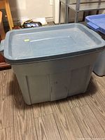 Closed large grey plastic tote container with lid shown from above and side
