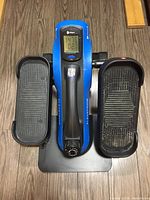 Top-down view of the blue Lifepro FlexStride Plus pedal exercise machine showing digital display, left and right textured pedals, resistance knob, handle, and base.