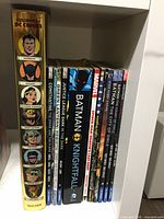 Side view of graphic novels and comic books featuring DC Comics characters including Superman, Batman, Wonder Woman, Green Lantern, Justice League Dark, Marvel Civil War, Star Wars, and Batman Knightfall.