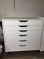 Front view of white IKEA ALEX drawer unit with six drawers and drawer handles.