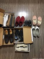 Photo showing nine pairs of women's shoes comprising steel toe, casual, and sneakers in various colors and styles, some in boxes.