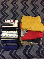 Stack of assorted folded clothing showing various colors including yellow, red, gray, and white