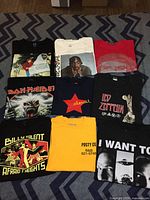 Full view of nine assorted graphic T-shirts arranged in a grid on floor, showing designs and colors