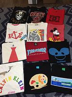 Overview of all 12 T-shirts in the lot arranged on bed