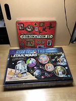 Photo showing all three board games stacked: Coronation Street on top, Star Wars Adventures of R2-D2 in the middle, and Star Trek The Game on bottom.