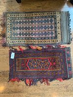 Two handwoven Afghan pillow bags side by side on wooden floor, showing full patterns and size difference