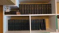 Top shelf with the Charles Dickens book set, showing 19 volumes with gilt titles on dark cloth bindings.