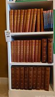 Bookshelf with multiple volumes of The Windsor Shakespeare in decorative red hardcovers and James Russell Lowell books in brown hardcovers.