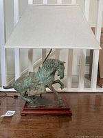 Full view of lamp showing the horse sculpture, wooden base, and cream rectangular lampshade.