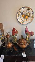 Overall view: plate on wall, roosters and metal vessels on counter