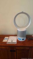 Full frontal view of the Dyson fan on wooden cabinet with two printed manuals laid out