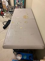 Top view of foldable table showing paint stains and wear on beige plastic surface.