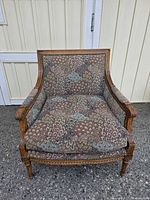 Front view of the armchair showing the patterned upholstery and carved wood frame details.