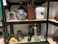 Shelving unit with various kitchen utensils and appliances including juicers and hand tools